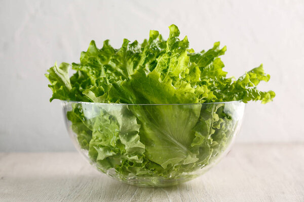 lettuce leaves in glass bowl on white background