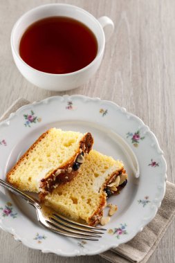 bir fincan çay ile beyaz seramik tabakta badem ve yaban mersini ile pasta dilimlenmiş