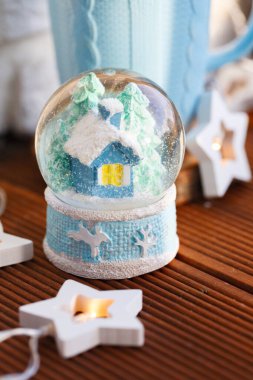 İçinde mavi bir kupanın arka planında bir ev olan kar Noel küresi..