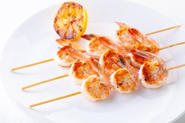 Şişte ızgara karides. Baharatlı ve limonlu ızgara deniz ürünleri. Lezzetli karides. Beyaz tabak. Minimalizm