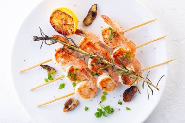 Şişte ızgara karides. Baharatlı, otlu ve limonlu ızgara deniz ürünleri. Lezzetli karides. Beyaz tabak. Beyaz arkaplan