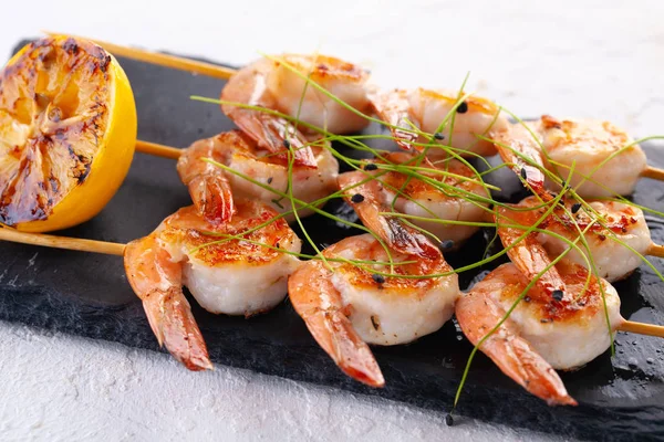 grilled shrimp on skewers. Grilled seafood on skewers with spices, herbs and lemon. delicious prawn. Black stone plate