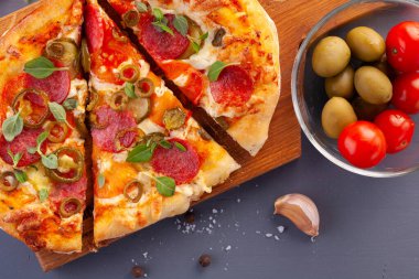 Ev yapımı baharatlı biberli pizza ve yemek malzemeleri. Gri ahşap bir masada Pepperoni pizza..