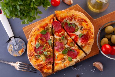 Ev yapımı baharatlı biberli pizza ve yemek malzemeleri. Gri ahşap bir masada Pepperoni pizza..
