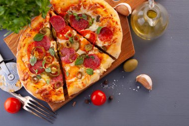 Ev yapımı baharatlı biberli pizza ve yemek malzemeleri. Gri ahşap bir masada Pepperoni pizza..