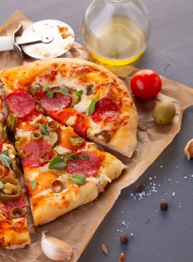 Ev yapımı baharatlı biberli pizza ve yemek malzemeleri. Gri ahşap bir masada Pepperoni pizza..
