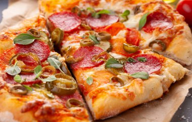 Ev yapımı baharatlı biberli pizza ve yemek malzemeleri. Gri ahşap bir masada Pepperoni pizza..