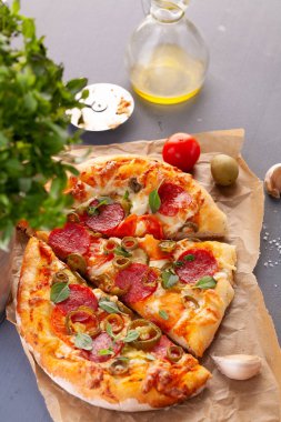 Ev yapımı baharatlı biberli pizza ve yemek malzemeleri. Gri ahşap bir masada Pepperoni pizza..