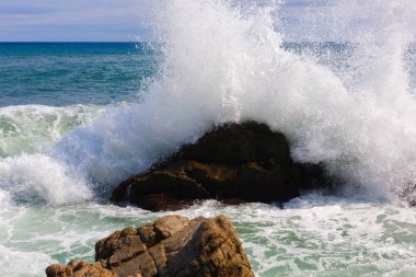 Dalgalardaki köpüğün görüntüsü. Dalga kayalarda kırılır. Doğa, deniz manzarası. İspanya.