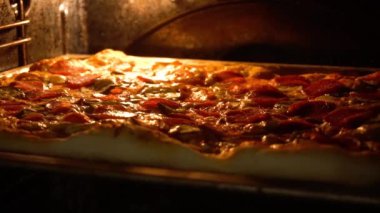 Pizzanın üzerindeki peynir fırının sıcaklığından erir. Lezzetli İtalyan pizza salamı ve peynirli fırında kızartılmış.