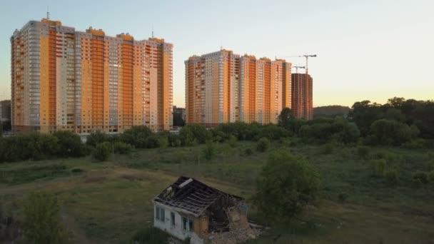 Une vieille maison en ruine solitaire se trouve à proximité de nouveaux immeubles d'appartements de plusieurs étages. Vue aérienne — Video