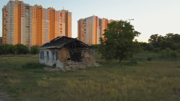 Una vieja y solitaria casa en ruinas está cerca con nuevos edificios de apartamentos de varios pisos. Vista aérea — Vídeos de Stock