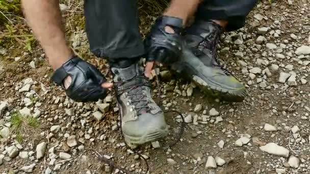 Trekking por las montañas. Un hombre se ata los cordones en los zapatos de trekking. Primer plano — Vídeo de stock