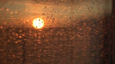 Su bir pencere camına sonra yağmur damlaları. Bulutlar ve arka plan üzerinde güneş ile gökyüzü.