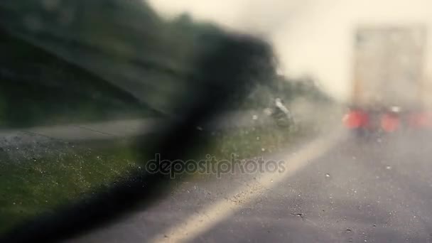 Blick auf die Straße aus dem Auto im Regen. Fokus auf die Windschutzscheibe. Die Straße steht im Fokus. Nahaufnahme — Stockvideo