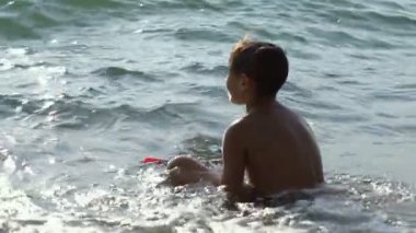 Bir çocuk bir maske ve şnorkel bir tüp ile denizde banyoları