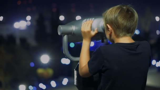 Boy tourist looking through binoculars at night city. Close-up — Stock Video