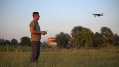Bir adam bir dron bir çayır üzerinde yaz aylarında gün batımında kontrol eder
