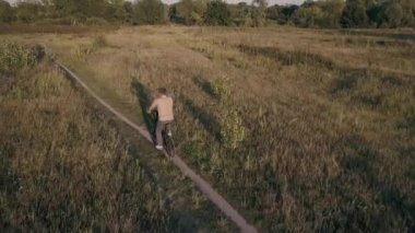 Bir adam bir çayırda bir Bisiklete biniyor. Havadan görünümü