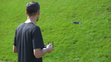 Bir adam bir çim yeşil çim üzerinde bir dron kontrol eder.