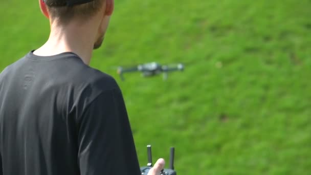 Чоловік контролює безпілотник на газоні з зеленою травою — стокове відео