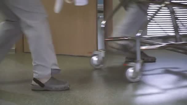 Врачи возят пациента на носилках в реанимацию. Ноги крупным планом — стоковое видео