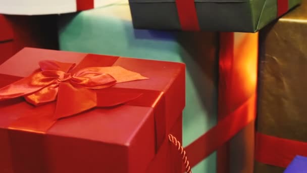 Под елкой лежат разноцветные коробки с подарками. Рождественские подарки в праздничной упаковке. Крупный план — стоковое видео