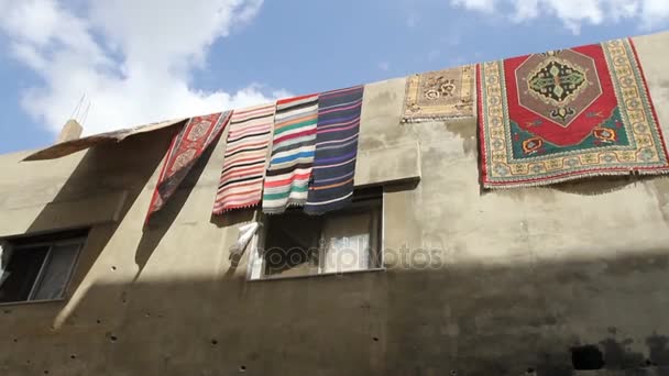 Homs, Sýrie, září 2013. Koberce jsou sušeny na stěně činžovního domu. Zdi v domě je poničen fragmenty po bitvách — Stock video