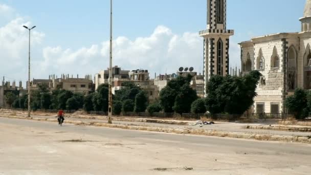 Homs, Sýrie, září 2013: Dva kluci jezdí na kole v blízkosti zničeného mešita v Homsu — Stock video
