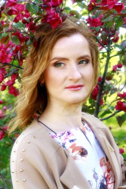 Bir elma bahçesi genç güzel kız. Kızıl saçlı kız portresi.