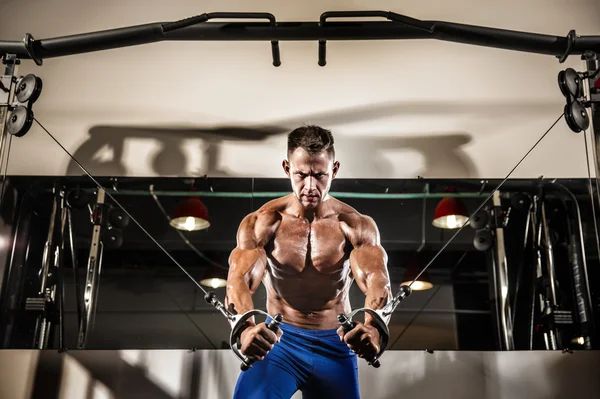 Jeune bodybuilder travaille sur sa poitrine avec câble croisé dans la salle de gym — Photo