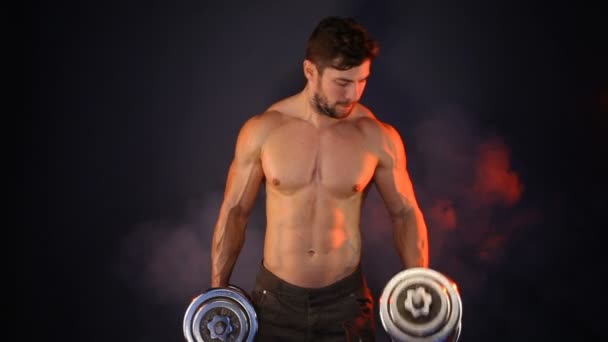 Сильный спортсмен поднимает тяжелые гантели в дыму — стоковое видео