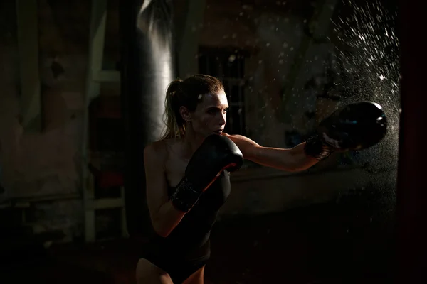 Mulher de boxe em corpo preto batendo saco de perfuração . — Fotografia de Stock