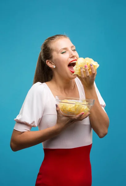 Jovem fêmea comendo batata frita enquanto assiste a um filme na superfície  branca