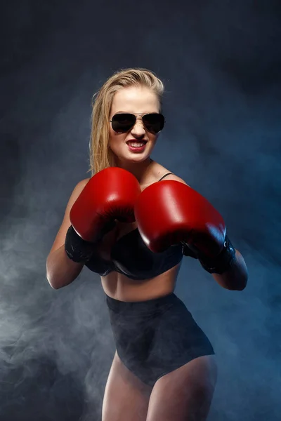 Lány szép szexi szőke boxer öltözött, vörös kesztyű, napszemüveg és fekete fehérnemű. Stúdió fiatal harcos nő portréja. füst. — Stock Fotó