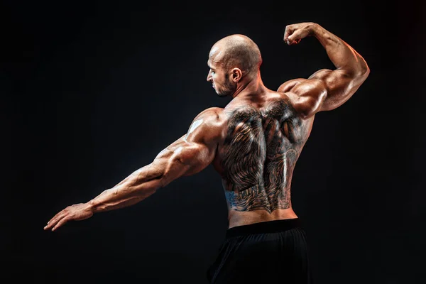 Vista posteriore del bodybuilder tatuato con le braccia tese — Foto Stock