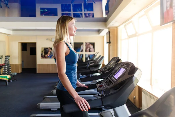 Mujer joven en el gimnasio haciendo ejercicio. Ejecutar en una máquina . —  Fotos de Stock