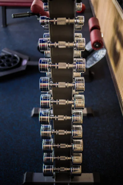 Sport Background. Rack of dumbbells in health club. Shelf with metal on gym studio room backdrop. — Stock Photo, Image