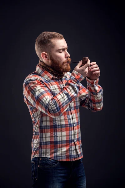 Elegante hombre barbudo sosteniendo pipa humeante — Foto de Stock