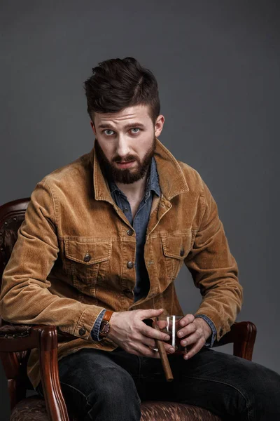Portrait of serious bearded man with cigar and whisky