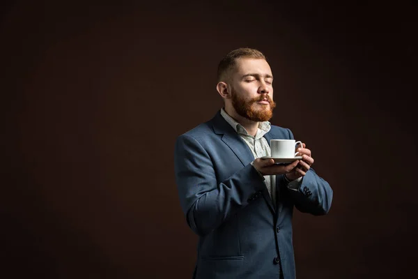 Handsome bearded man enjoying smell of coffee