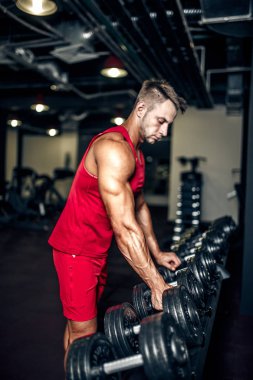 Yakışıklı kaslı adam spor salonunda çalışıyor ve poz veriyor.