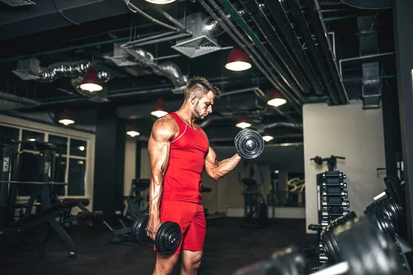 Bodybuilder déterminé soulevant haltères noirs lourds à la salle de gym . — Photo