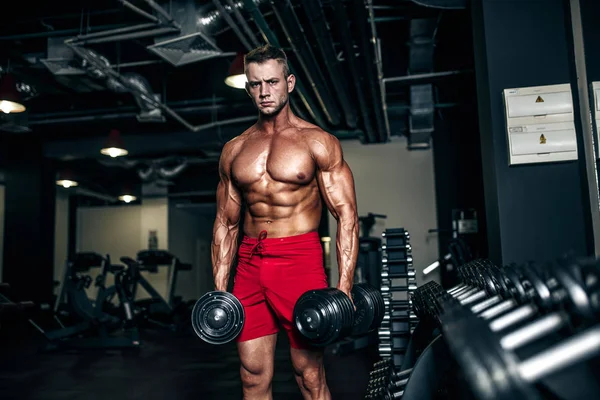 Przystojny muskularny mężczyzna ćwiczy i pozuje na siłowni — Zdjęcie stockowe