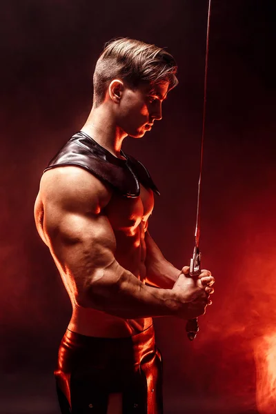Portrait of sexy muscular concentrated man holding sword. — Stock Photo, Image
