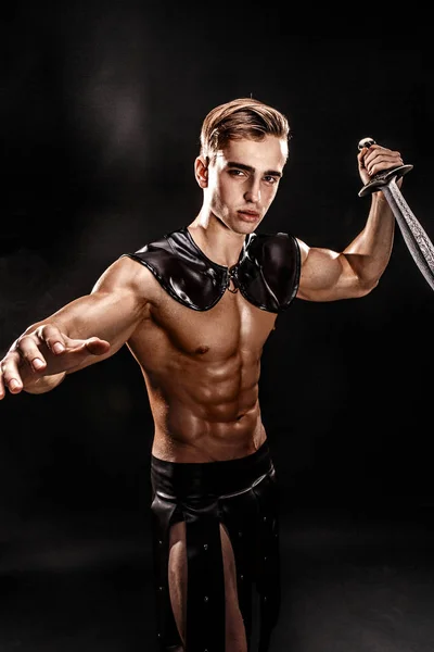 Portret van knappe gespierde gladiator met zwaard. Geïsoleerd. Studio opname. Zwarte achtergrond — Stockfoto