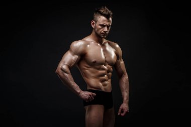 Stüdyoda siyah arka planda poz veren yakışıklı erkek model..