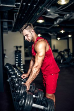 Yakışıklı kaslı adam spor salonunda çalışıyor ve poz veriyor.