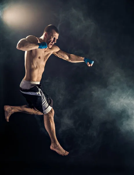 Kickbox musculaire ou muay thai boxeur poinçonnage en saut. Fumée . — Photo