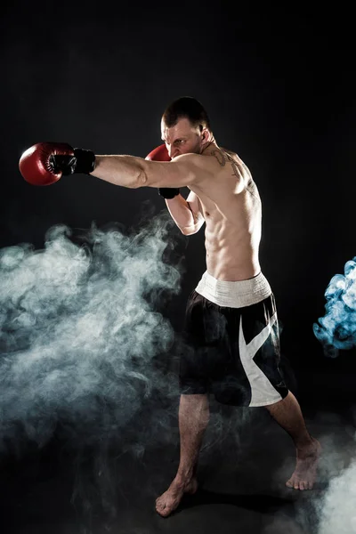 Muscular kickbox o muay thai luchador puñetazos en el humo . —  Fotos de Stock